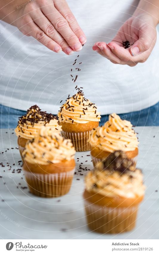 Frau bereitet köstliche Thanksgiving Cupcakes zu. Erntedankfest Orange Hintergrundbild Dessert weiß Saison Zuckerguß Herbst Schokolade vereinzelt