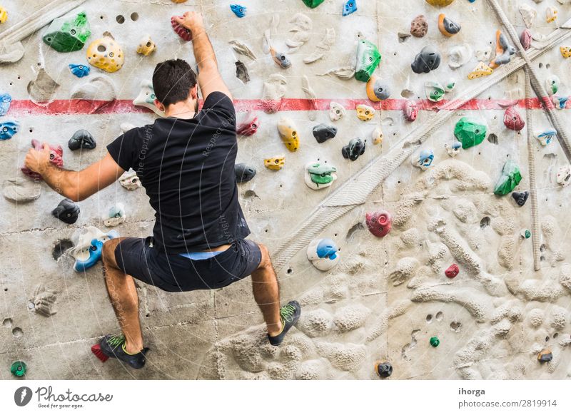 Mann übt Klettern an einer künstlichen Wand in Innenräumen. Lifestyle Freude Freizeit & Hobby Sport Bergsteigen Mensch Junger Mann Jugendliche Erwachsene 1