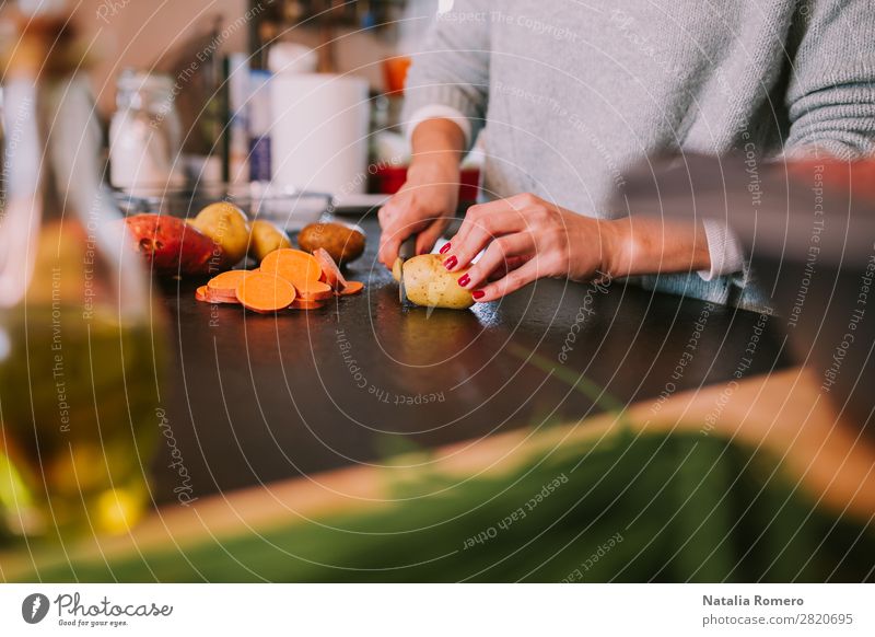 eine Person, die Kartoffeln und Süßkartoffeln in einer schönen Küche schneidet. Gemüse Essen Mittagessen Abendessen Diät Tisch Mensch Frau Erwachsene Hand Natur