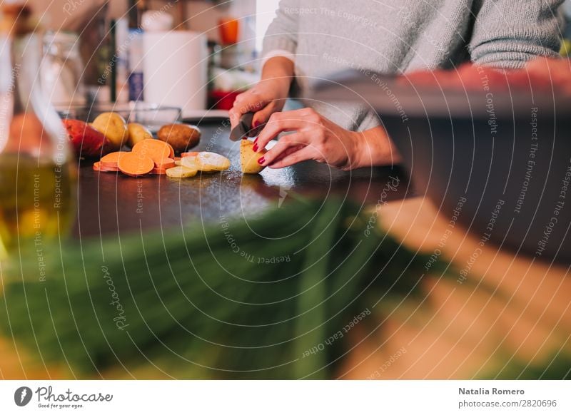 eine Person, die Kartoffeln und Süßkartoffeln in einer schönen Küche schneidet. Gemüse Essen Mittagessen Abendessen Diät Tisch Mensch Frau Erwachsene Hand Natur