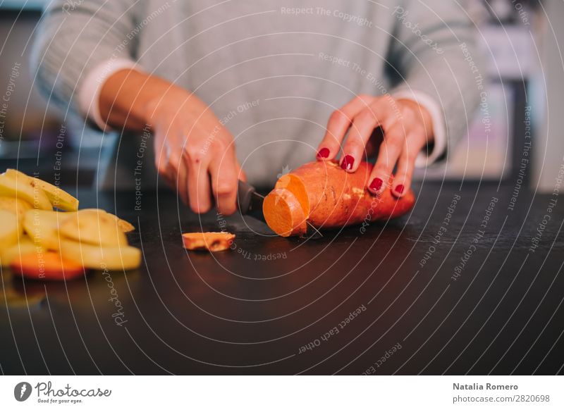 eine Person, die Kartoffeln und Süßkartoffeln in einer schönen Küche schneidet. Gemüse Essen Mittagessen Abendessen Diät Tisch Mensch Frau Erwachsene Hand Natur