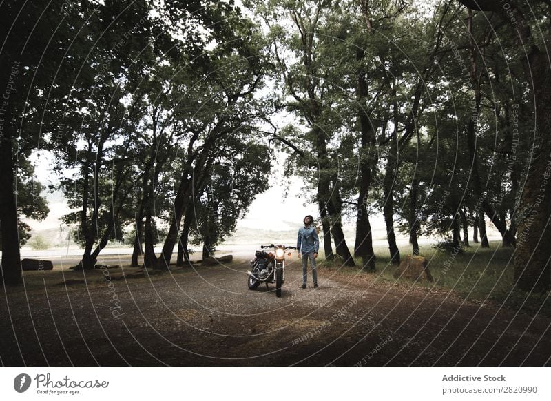 Mann, der mit dem Motorrad auf der Landschaft posiert. Felsen Klippe Fernweh Verkehr Ferien & Urlaub & Reisen See Motorradsportler stehen Freiheit Bahn