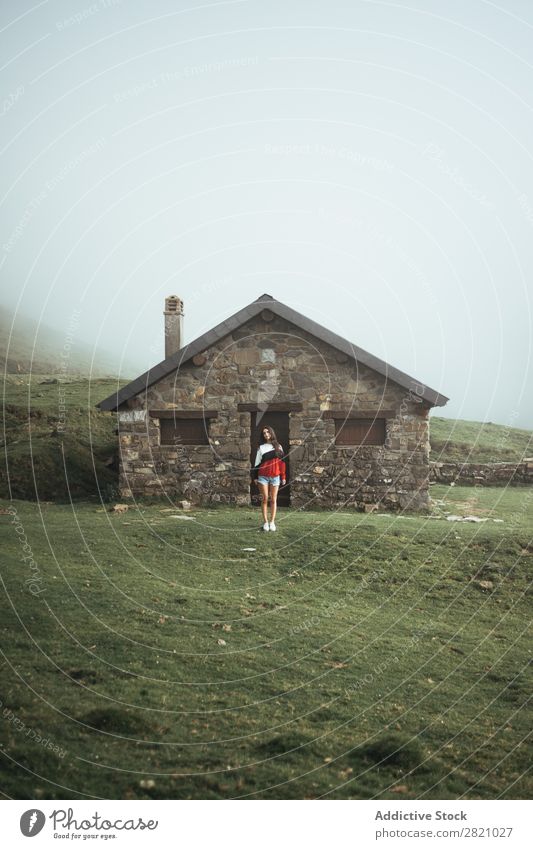 Frau, die im ländlichen Haus steht. Landschaft Natur Gras grün Länder Jugendliche Lifestyle schön Dorf lässig Porträt Konstruktion Cottage Gebäude heimisch