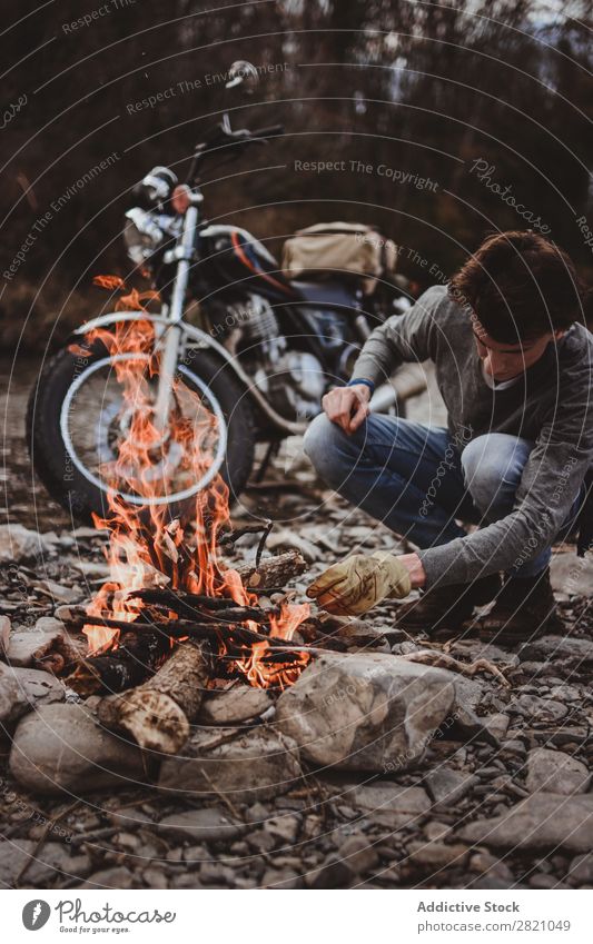 Reisender, der Lagerfeuer hält Mann Feuerstelle Motorrad Einsamkeit Expedition Flamme Brennholz Fernweh Aktion Abenteuer reisend Tourismus wandern Verkehr