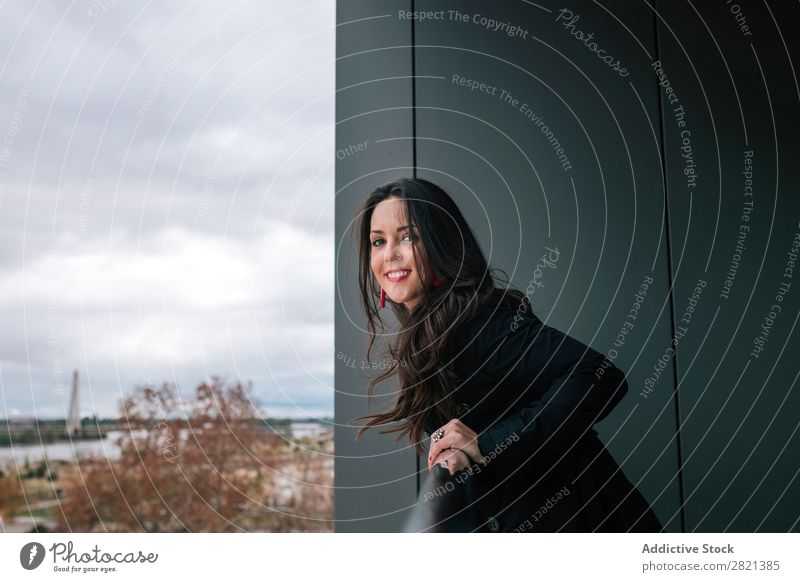 Fröhliche Frau am Handlauf stehend hübsch Jugendliche schön heiter Lächeln Balkon Gebäude modern Zeitgenosse brünett attraktiv Mensch Beautyfotografie