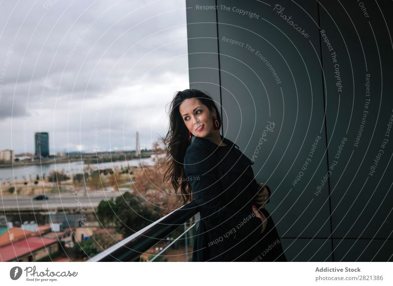 Fröhliche Frau am Handlauf stehend hübsch Jugendliche schön heiter Lächeln Balkon Gebäude modern Zeitgenosse brünett attraktiv Mensch Beautyfotografie