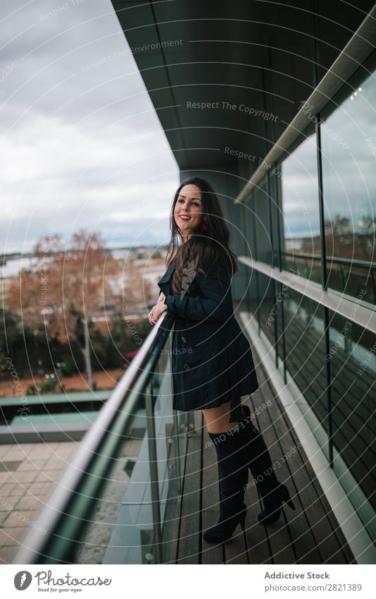 Fröhliche Frau am Handlauf stehend hübsch Jugendliche schön heiter Lächeln Balkon Gebäude modern Zeitgenosse brünett attraktiv Mensch Beautyfotografie