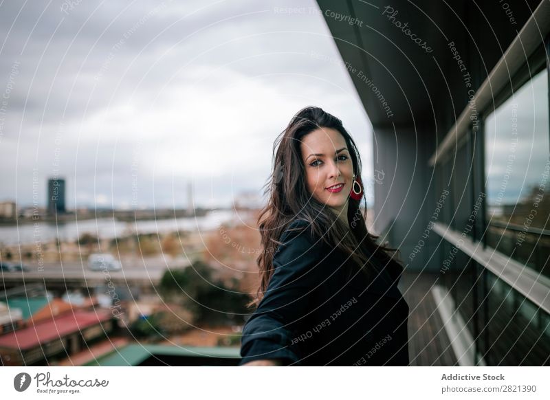 Fröhliche Frau am Handlauf stehend hübsch Jugendliche schön heiter Lächeln Balkon Gebäude modern Zeitgenosse brünett attraktiv Mensch Beautyfotografie