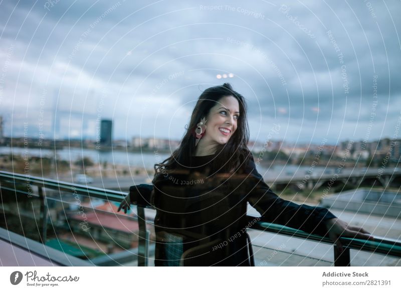 Fröhliche Frau am Handlauf stehend hübsch Jugendliche schön heiter Lächeln Balkon Gebäude modern Zeitgenosse brünett attraktiv Mensch Beautyfotografie