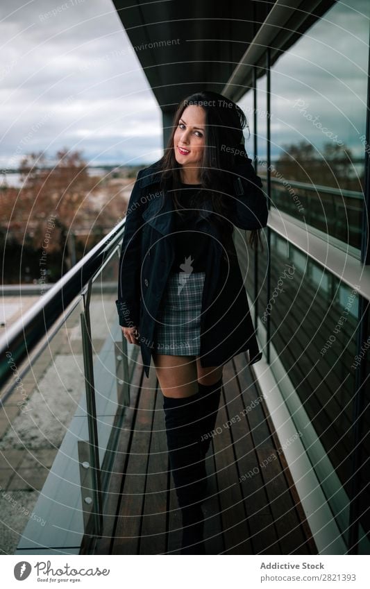 Fröhliche Frau am Handlauf stehend hübsch Jugendliche schön heiter Lächeln Balkon Gebäude modern Zeitgenosse brünett attraktiv Mensch Beautyfotografie