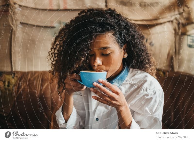 Frau trinkt eine Tasse Kaffee. schön urwüchsig schwarz Jugendliche Afrikanisch rühren Latte brünett attraktiv Mensch Beautyfotografie Erwachsene Stil niedlich