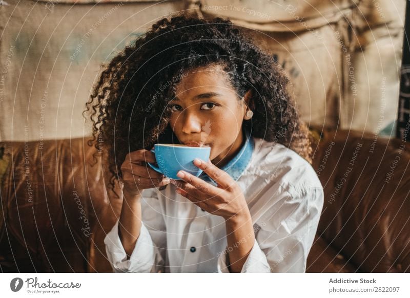 Frau trinkt eine Tasse Kaffee. schön urwüchsig schwarz Jugendliche Afrikanisch rühren Latte brünett attraktiv Mensch Beautyfotografie Erwachsene Stil niedlich