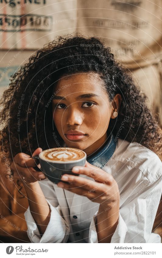 Frau trinkt eine Tasse Kaffee. schön urwüchsig schwarz Jugendliche Afrikanisch rühren Latte brünett attraktiv Mensch Beautyfotografie Erwachsene Stil niedlich