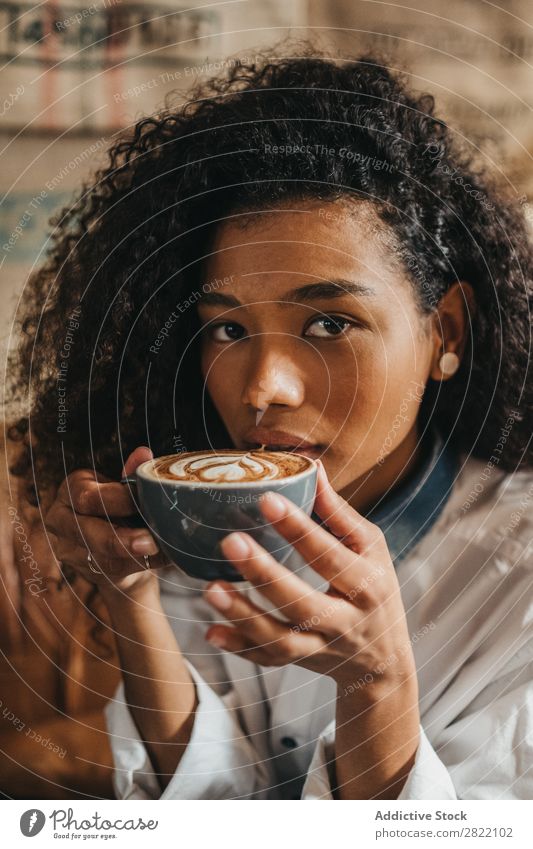 Frau trinkt eine Tasse Kaffee. schön urwüchsig schwarz Jugendliche Afrikanisch rühren Latte brünett attraktiv Mensch Beautyfotografie Erwachsene Stil niedlich