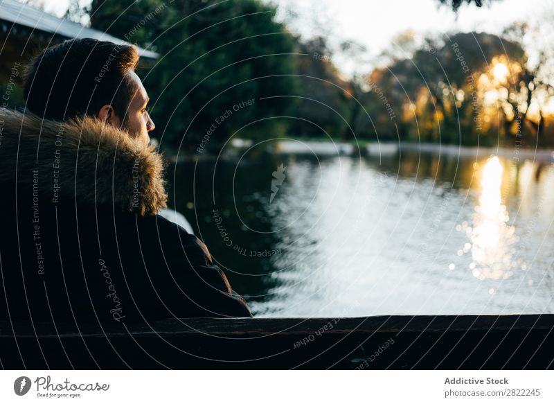 Mann sitzt und schaut auf den See. Park Teich Natur Wasser grün schön Wärme Jacke Jugendliche Jahreszeiten natürlich Mensch Wald Lifestyle Beautyfotografie