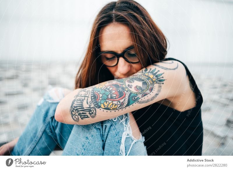 Frau mit Tattoos auf dem Bürgersteig sitzend Stil alt Straßenbelag Brillenträger Relief schön Jugendliche Mode Schickimicki hübsch Coolness Beautyfotografie