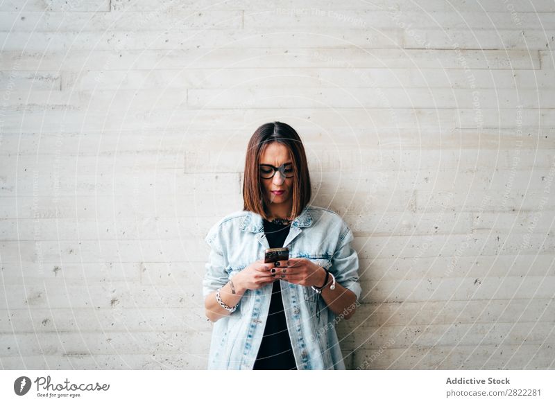 Frau mit Smartphone an der Betonwand Stil PDA anlehnen Wand benutzend Browsen Straße schön Jugendliche Mode Schickimicki hübsch Coolness Beautyfotografie