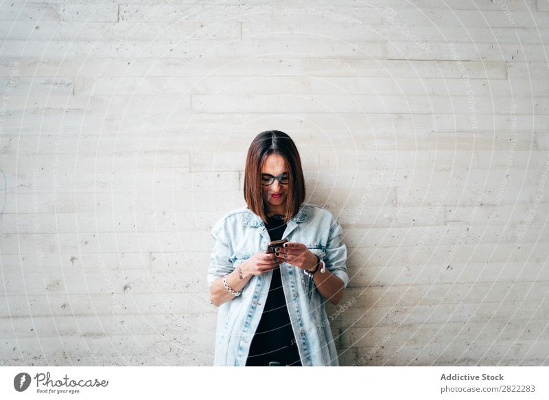 Frau mit Smartphone an der Betonwand Stil PDA anlehnen Wand benutzend Browsen Straße schön Jugendliche Mode Schickimicki hübsch Coolness Beautyfotografie