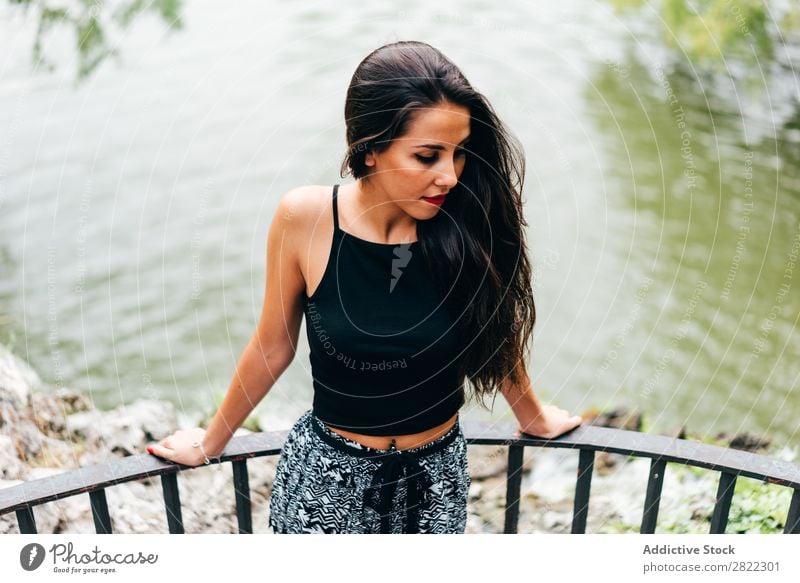 Brünette Frau, die sich auf den Handlauf am Fluss lehnt. hübsch Jugendliche schön brünett attraktiv Mensch Beautyfotografie Erwachsene Stil niedlich Lifestyle