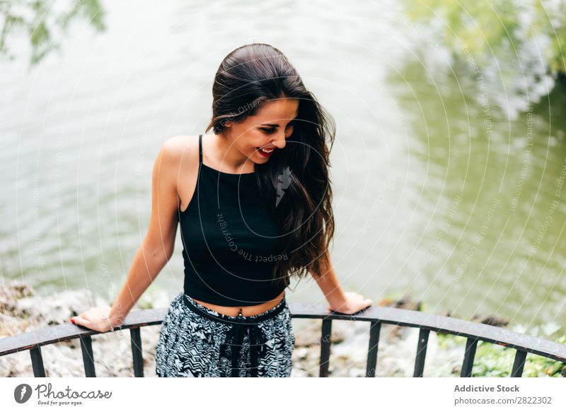 Brünette Frau, die sich auf den Handlauf am Fluss lehnt. hübsch Jugendliche schön brünett attraktiv Mensch Beautyfotografie Erwachsene Stil niedlich Lifestyle