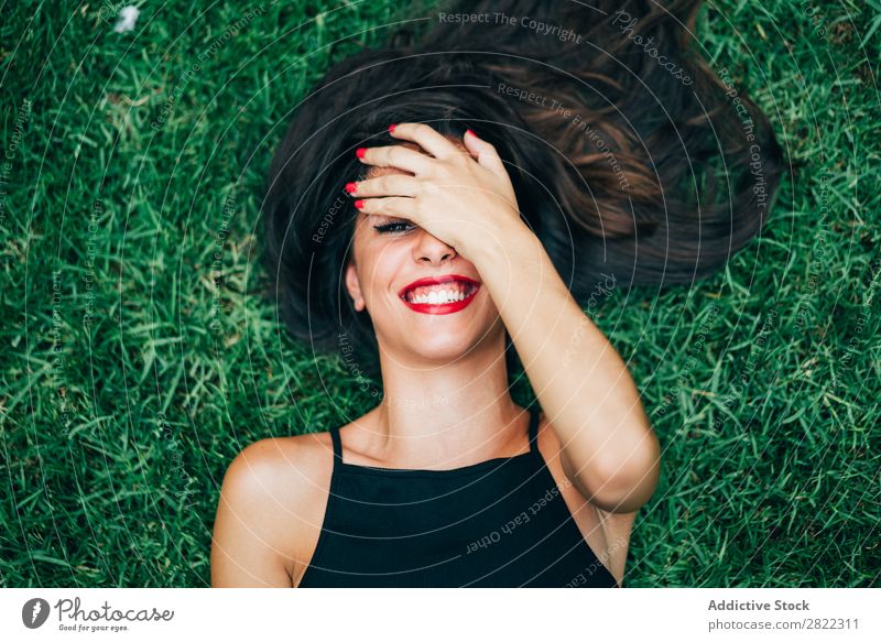 Fröhliche brünette Frau im Gras liegend hübsch Jugendliche schön heiter Lächeln lügen Natur Blick in die Kamera attraktiv Mensch Beautyfotografie Erwachsene