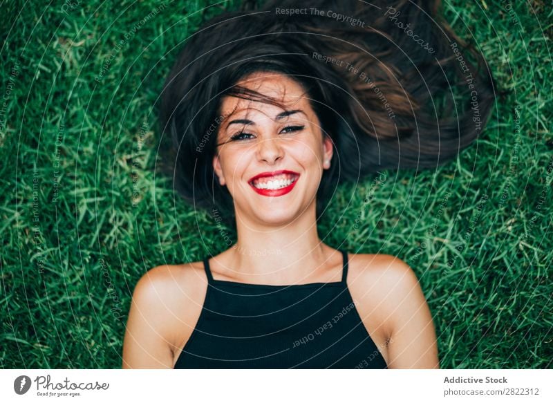 Fröhliche brünette Frau im Gras liegend hübsch Jugendliche schön heiter Lächeln lügen Natur Blick in die Kamera attraktiv Mensch Beautyfotografie Erwachsene