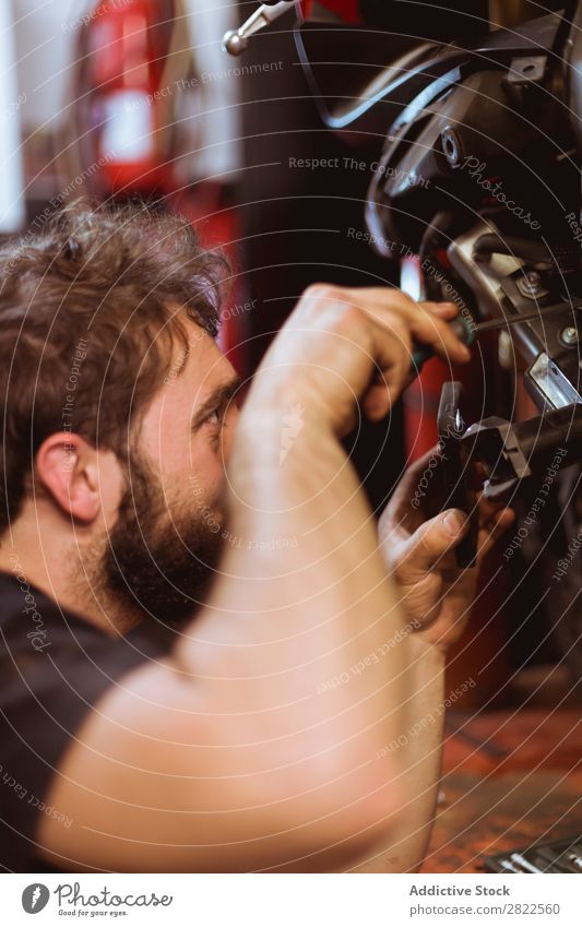 Person, die die Wartung des Fahrrads durchführt Mitarbeiter Mensch Blick inspizierend Motorrad Werkstatt geparkt Verkehr Fahrzeug Garage benutzerdefiniert