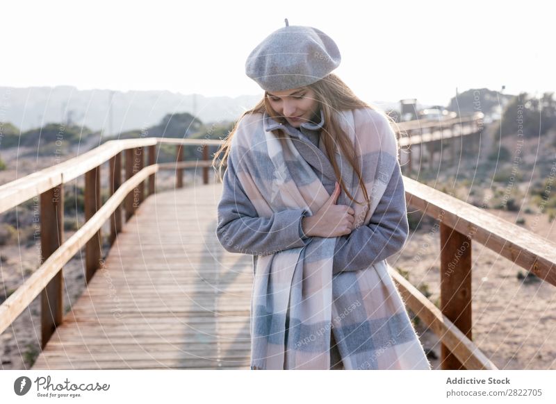 Fröhliche Frau an der Promenade stehend hübsch Jugendliche schön attraktiv heiter Lächeln Gang Holz Natur Stil Baskenmütze Mensch Mantel Beautyfotografie