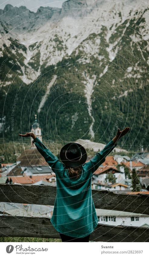 Frau steht vor der Bergstadt mit ausgestreckten Armen. Lifestyle Freude Ferien & Urlaub & Reisen Tourismus Abenteuer Sommer Berge u. Gebirge wandern feminin