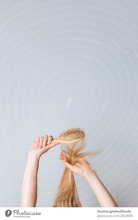 Blondes Haar mit einer Holzhaarbürste bürsten. Lifestyle schön Haare & Frisuren Gesundheitswesen Mensch Frau Erwachsene Arme Hand Mode blond Haarbürste lang