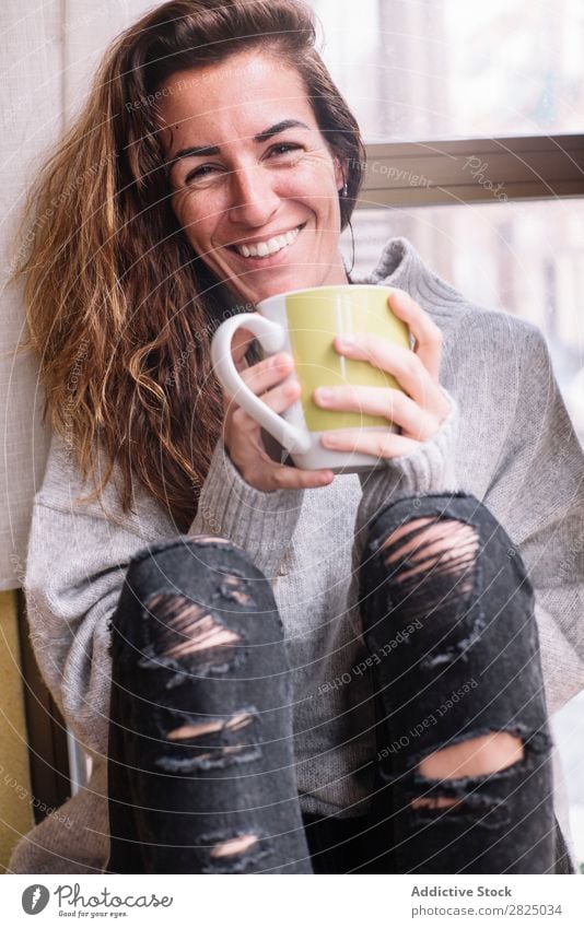 Fröhliche Frau entspannt sich bei einer Tasse. heimwärts Erholung Lifestyle Becher trinken heiß Lächeln Kaffee Tee schön Raum Mensch lässig Erwachsene Haus