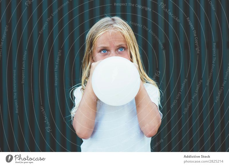 Mädchen bläst Ballon draußen. Luftballon wehen Körperhaltung ernst emotionslos Stadt Kindheit aufblasend Geburtstag Jugendliche Porträt Party Gesichtsbehandlung