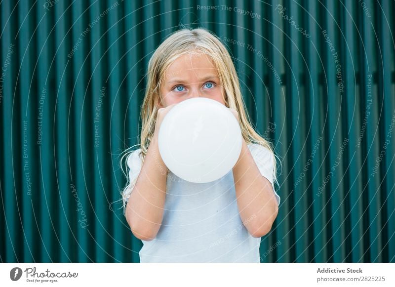 Mädchen bläst Ballon draußen. Luftballon wehen Körperhaltung ernst emotionslos Stadt Kindheit aufblasend Geburtstag Jugendliche Porträt Party Gesichtsbehandlung