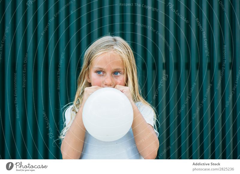 Mädchen bläst Ballon draußen. Luftballon wehen Körperhaltung ernst emotionslos Stadt Kindheit aufblasend Geburtstag Jugendliche Porträt Party Gesichtsbehandlung