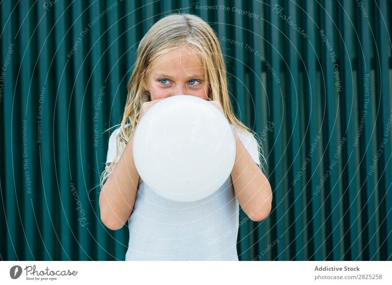 Mädchen bläst Ballon draußen. Luftballon wehen Körperhaltung ernst emotionslos Stadt Kindheit aufblasend Geburtstag Jugendliche Porträt Party Gesichtsbehandlung