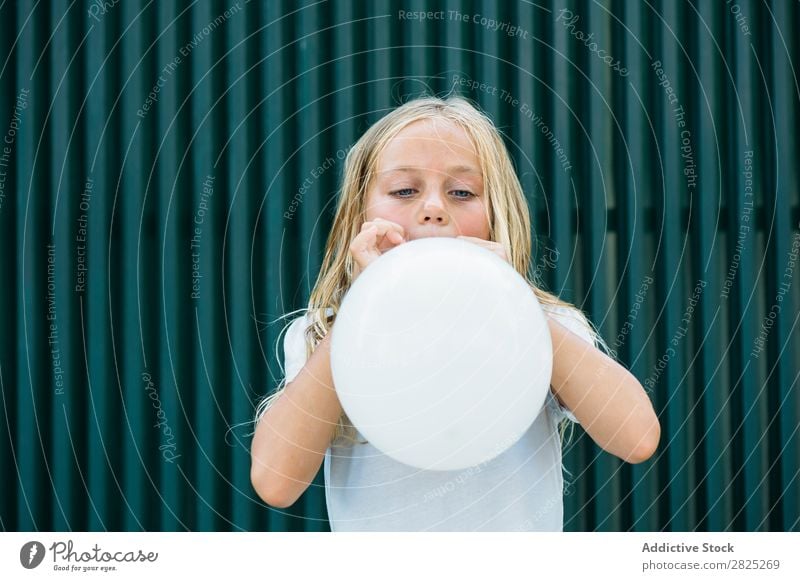 Mädchen bläst Ballon draußen. Luftballon wehen Körperhaltung ernst emotionslos Stadt Kindheit aufblasend Geburtstag Jugendliche Porträt Party Gesichtsbehandlung