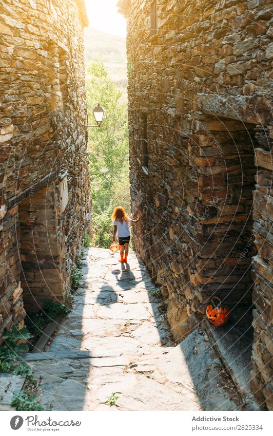 Verspieltes Mädchen auf der Straße an Halloween spielerisch Körperhaltung Kürbis Herbst Kind Kindheit heiter Tradition Bekleidung einzigartig Sonnenlicht