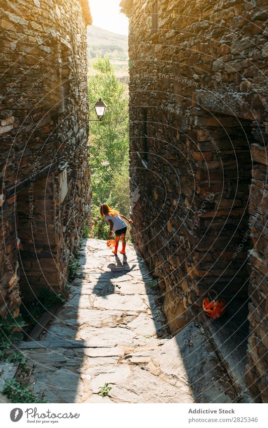 Verspieltes Mädchen auf der Straße an Halloween spielerisch Körperhaltung Kürbis Herbst Kind Kindheit heiter Tradition Bekleidung einzigartig Sonnenlicht