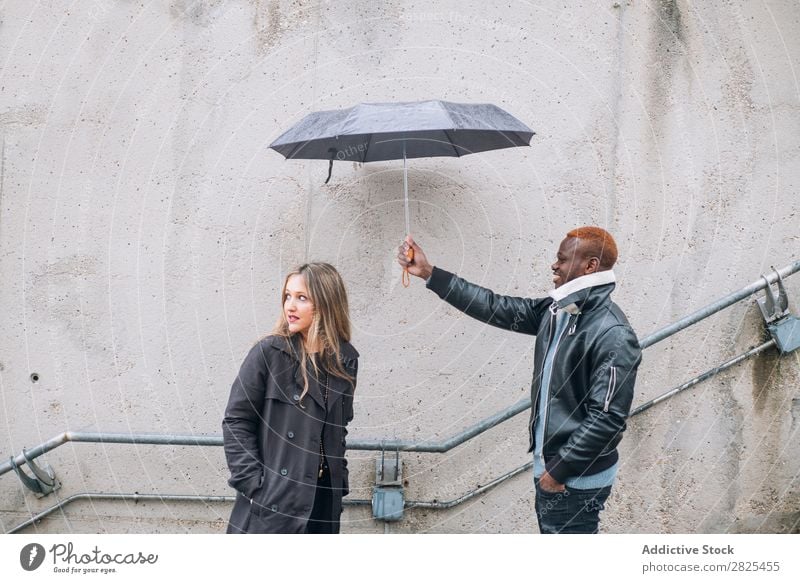 Freunde, die bei Regen auf der Straße spielen. Interrassische Beziehungen vielfältig Romantik 20s hübsch Amerikaner Lieblichkeit Partnerschaft Gesicht Körper