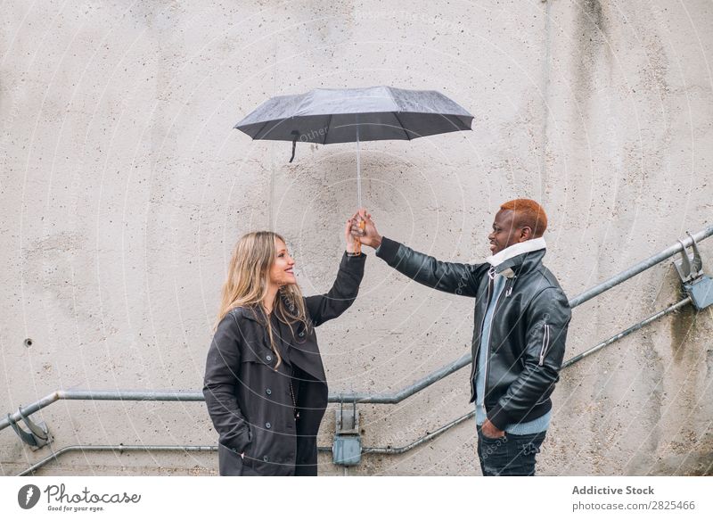 Freunde, die bei Regen auf der Straße spielen. Interrassische Beziehungen vielfältig Romantik 20s hübsch Amerikaner Lieblichkeit Partnerschaft Gesicht Körper