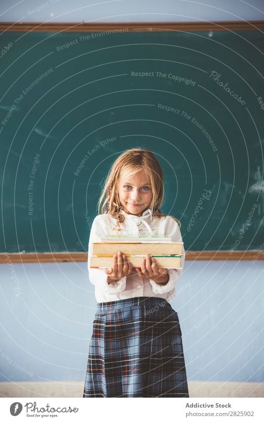 Schüler an der Tafel mit Büchern in der Hand Mädchen Klassenraum stehen heiter Glück Lächeln Buch Kreide niedlich Bildung Schule Schulklasse Jugendliche lernen