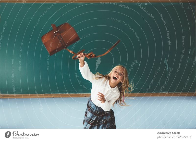 Mädchen wirft Rucksack im Klassenzimmer. Klassenraum Tafel Freude Werfen Ferien & Urlaub & Reisen Glück heiter stehen niedlich Bildung Schule Schulklasse