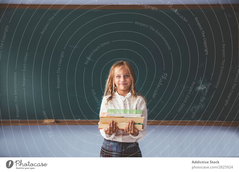 Schüler an der Tafel mit Büchern in der Hand Mädchen Klassenraum stehen heiter Glück Lächeln Buch Kreide niedlich Bildung Schule Schulklasse Jugendliche lernen