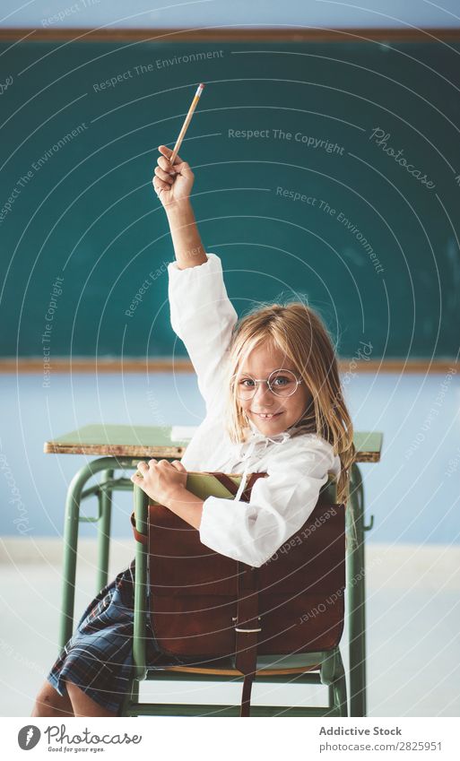 Lächelndes Mädchen mit Bleistift im Unterricht Klassenraum Tafel sitzen Blick in die Kamera Glück heiter hochreichen niedlich Bildung Schule Schulklasse Schüler