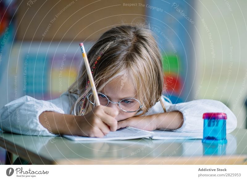 Nachdenkliches Mädchen beim Schreiben im Unterricht Klassenraum sitzen Schreibtisch schreibend Bleistift Zeichnung Denken Fürsorge gelangweilt niedlich Bildung