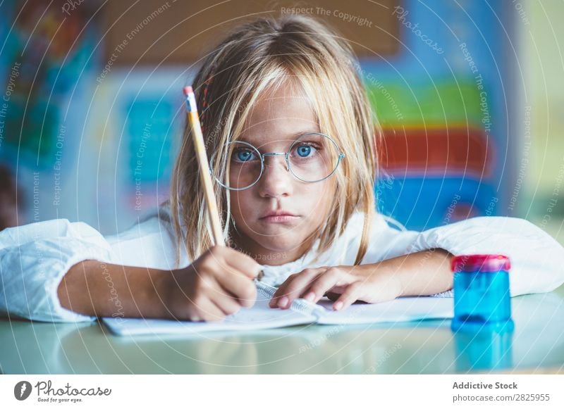 Nachdenkliches Mädchen beim Schreiben im Unterricht Klassenraum sitzen Schreibtisch schreibend Bleistift Zeichnung Denken Fürsorge gelangweilt niedlich Bildung