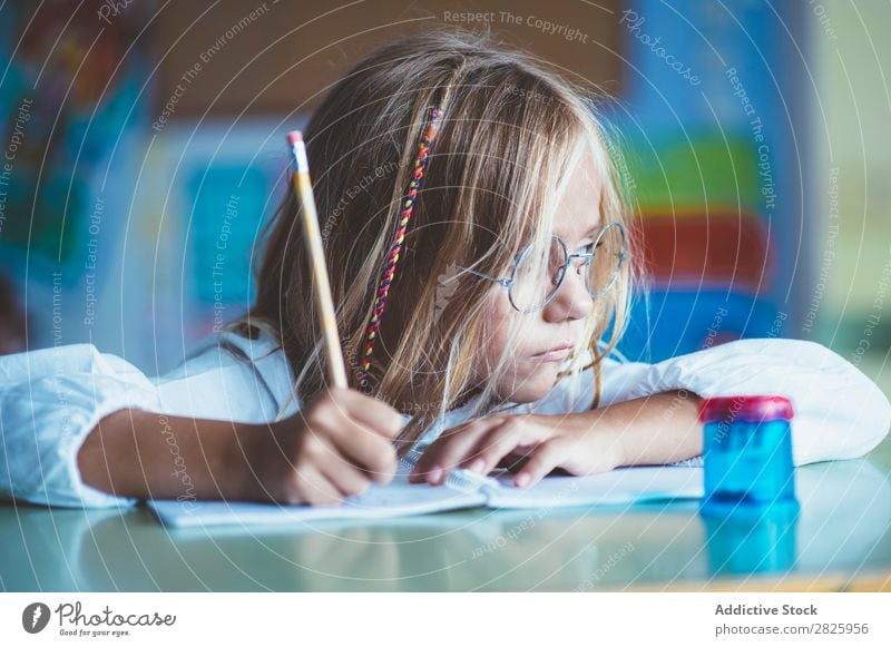 Nachdenkliches Mädchen beim Schreiben im Unterricht Klassenraum sitzen Schreibtisch schreibend Bleistift Zeichnung Denken Fürsorge gelangweilt niedlich Bildung