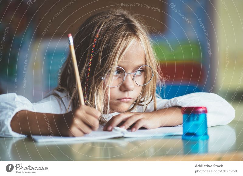 Nachdenkliches Mädchen beim Schreiben im Unterricht Klassenraum sitzen Schreibtisch schreibend Bleistift Zeichnung Denken Fürsorge gelangweilt niedlich Bildung