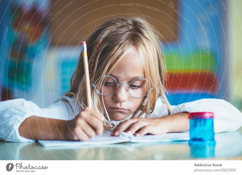 Nachdenkliches Mädchen beim Schreiben im Unterricht Klassenraum sitzen Schreibtisch schreibend Bleistift Zeichnung Denken Fürsorge gelangweilt niedlich Bildung