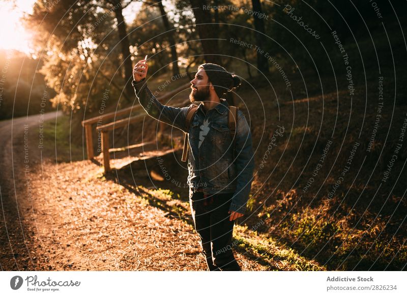 Mann mit Selfie auf sonniger Herbststraße Tourist Wald Porträt Rucksack Telefon Straße Technik & Technologie Tourismus Ferien & Urlaub & Reisen Abenteuer